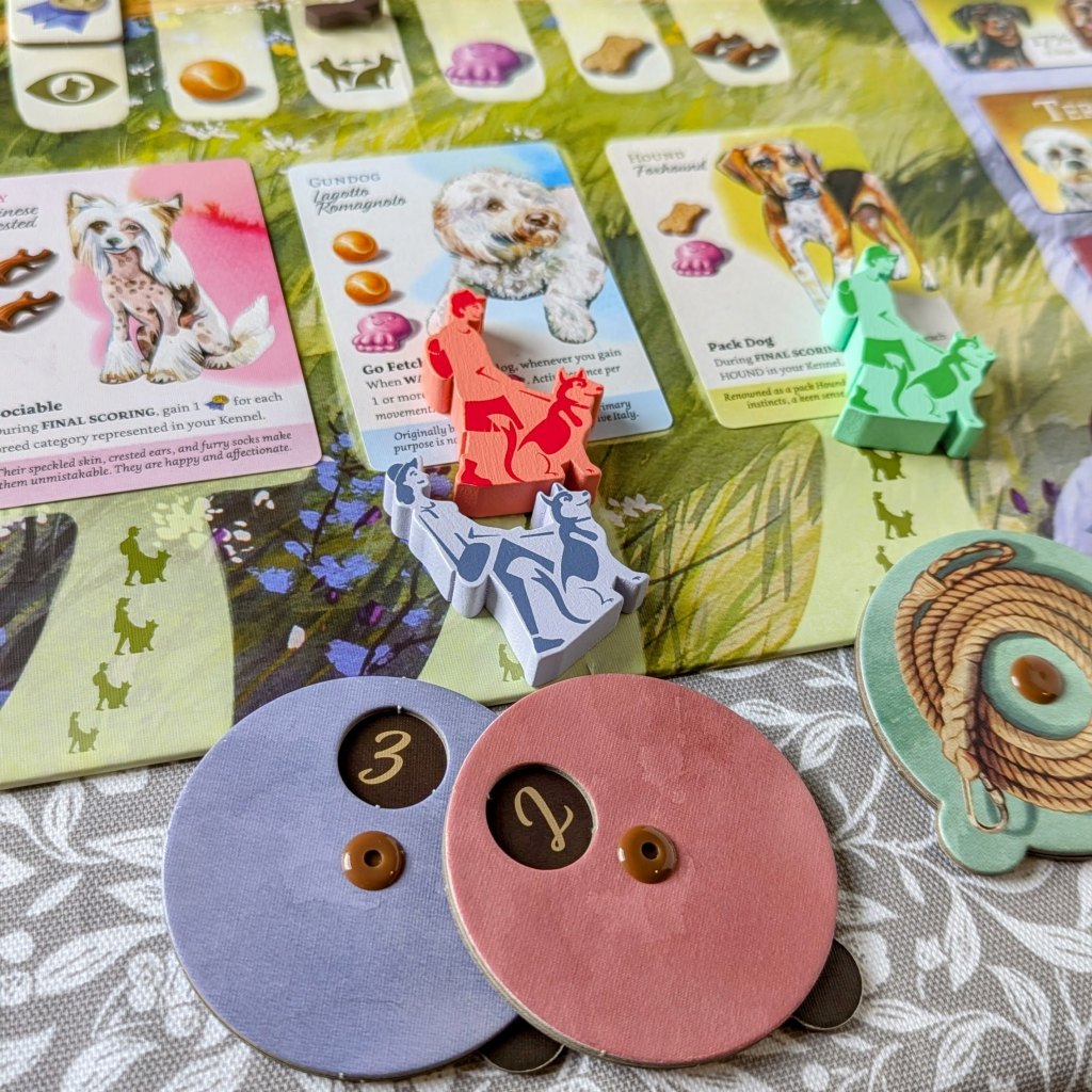 A zoomed in image of the field part of the board, where the red and blue player are bidding for dog cards. Underneath the board are the red and blue players Offer dials: red has reveal 2 and blue player has revealed a 3. Blue wins the dog, but has to pay 3 reputation points.