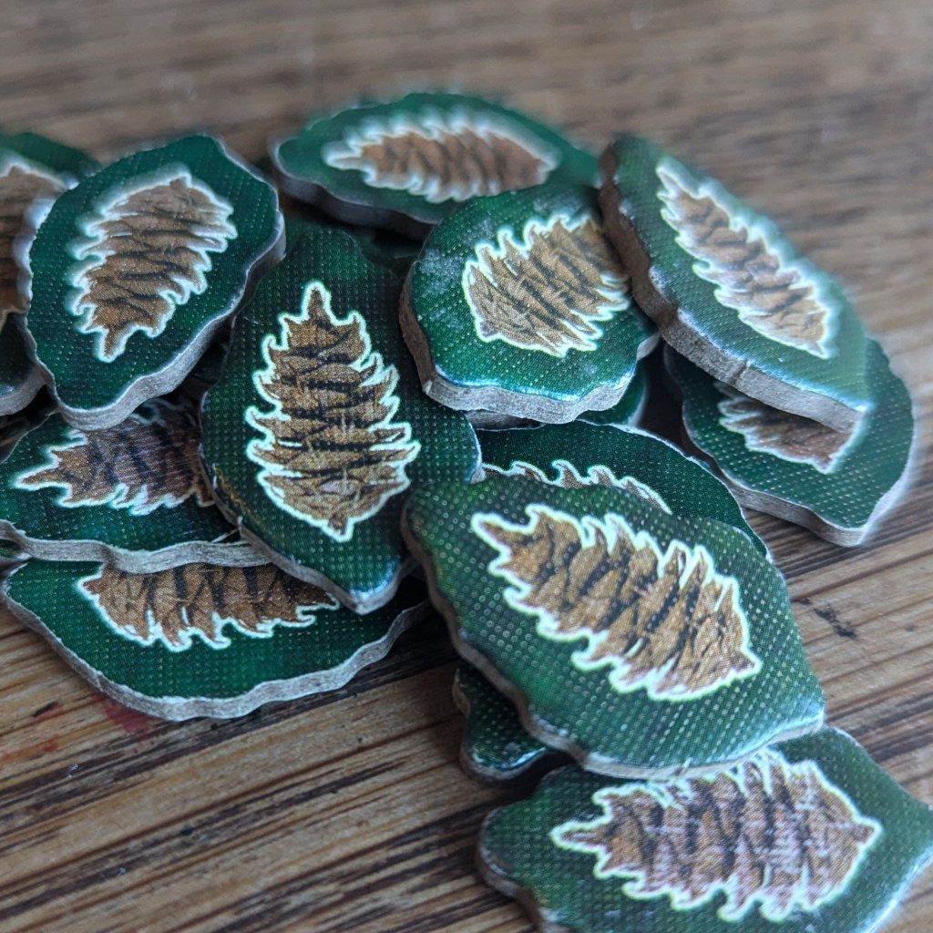 Cascadia nature tokens - small cardboard tokens of fir cones with a green outline