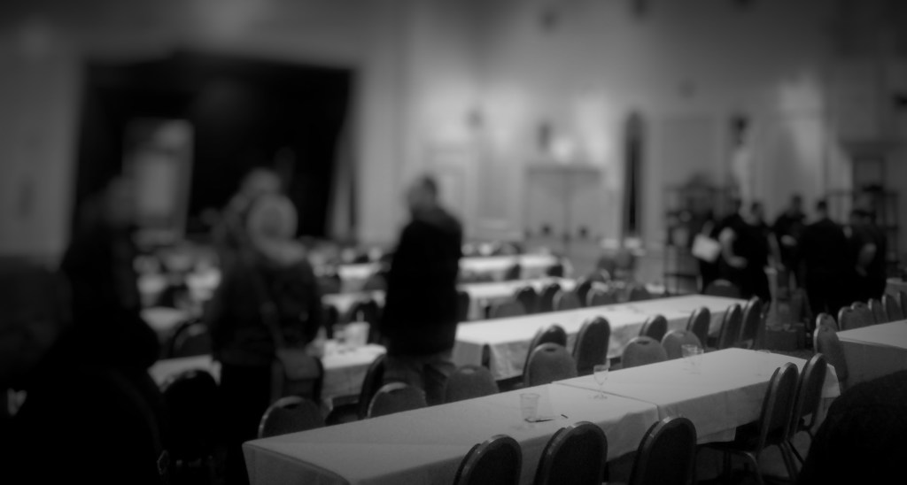 A black and white photo of the room at the end of the night, with empty tables and chairs.